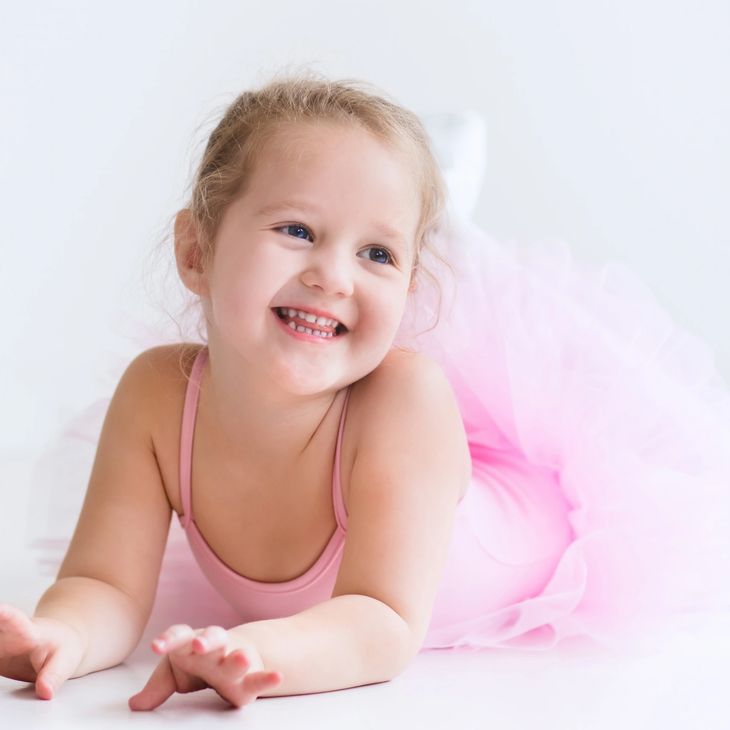 A pre-school dancer happily laying on her stomach after her Ballet Princess birthday party