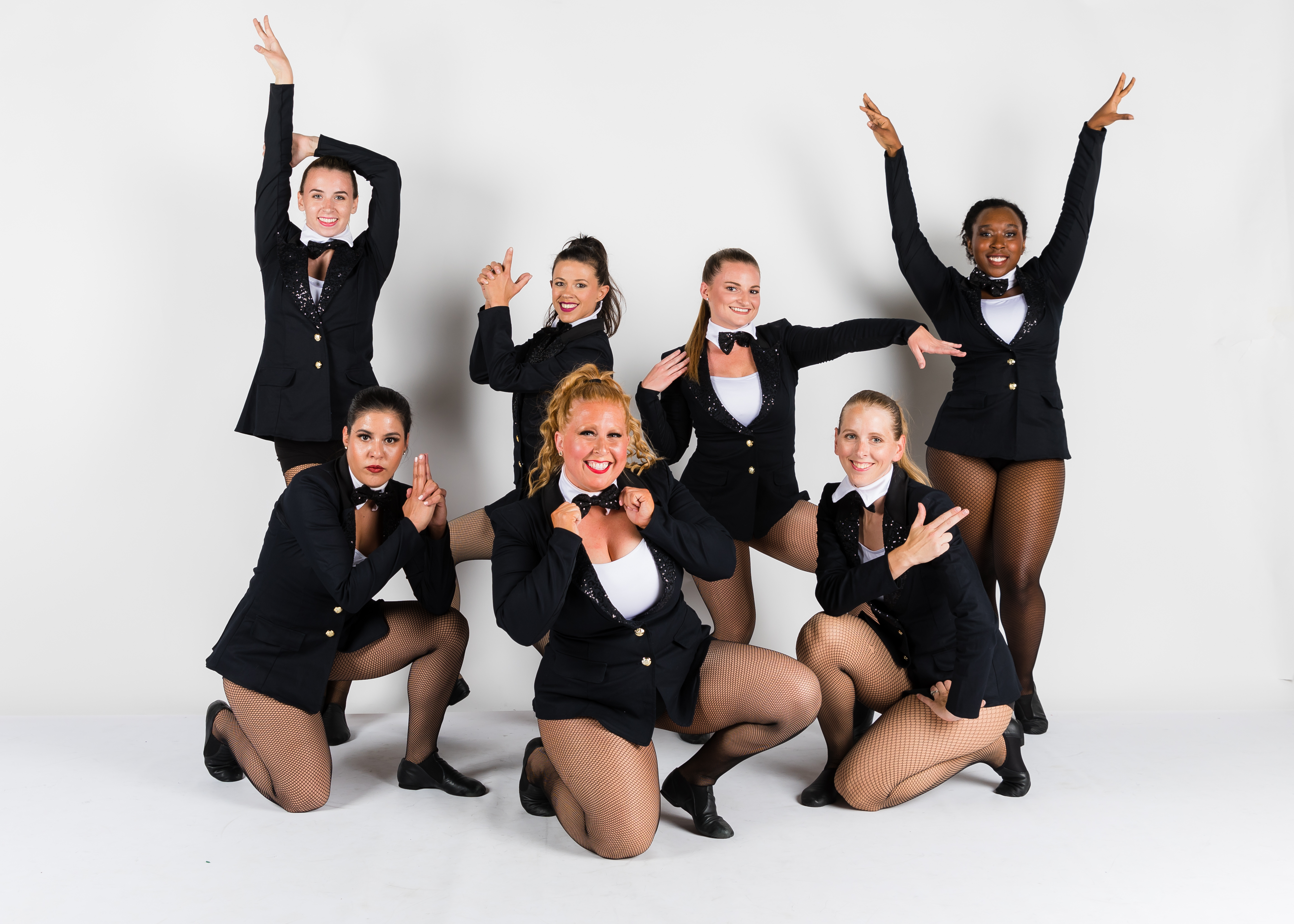 a group of adult tap dancers posing with pure joy at their recital performance