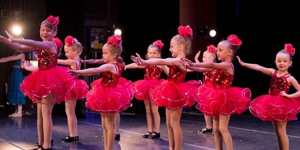 Young dancers shining on stage in sparkly costumes at the recital