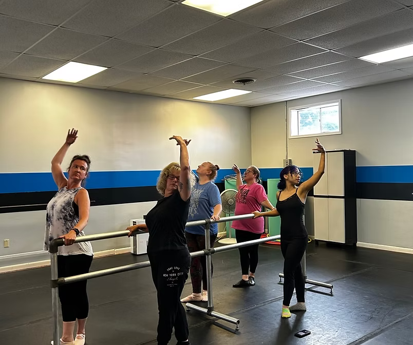 Adult dance students training ballet at the barrre