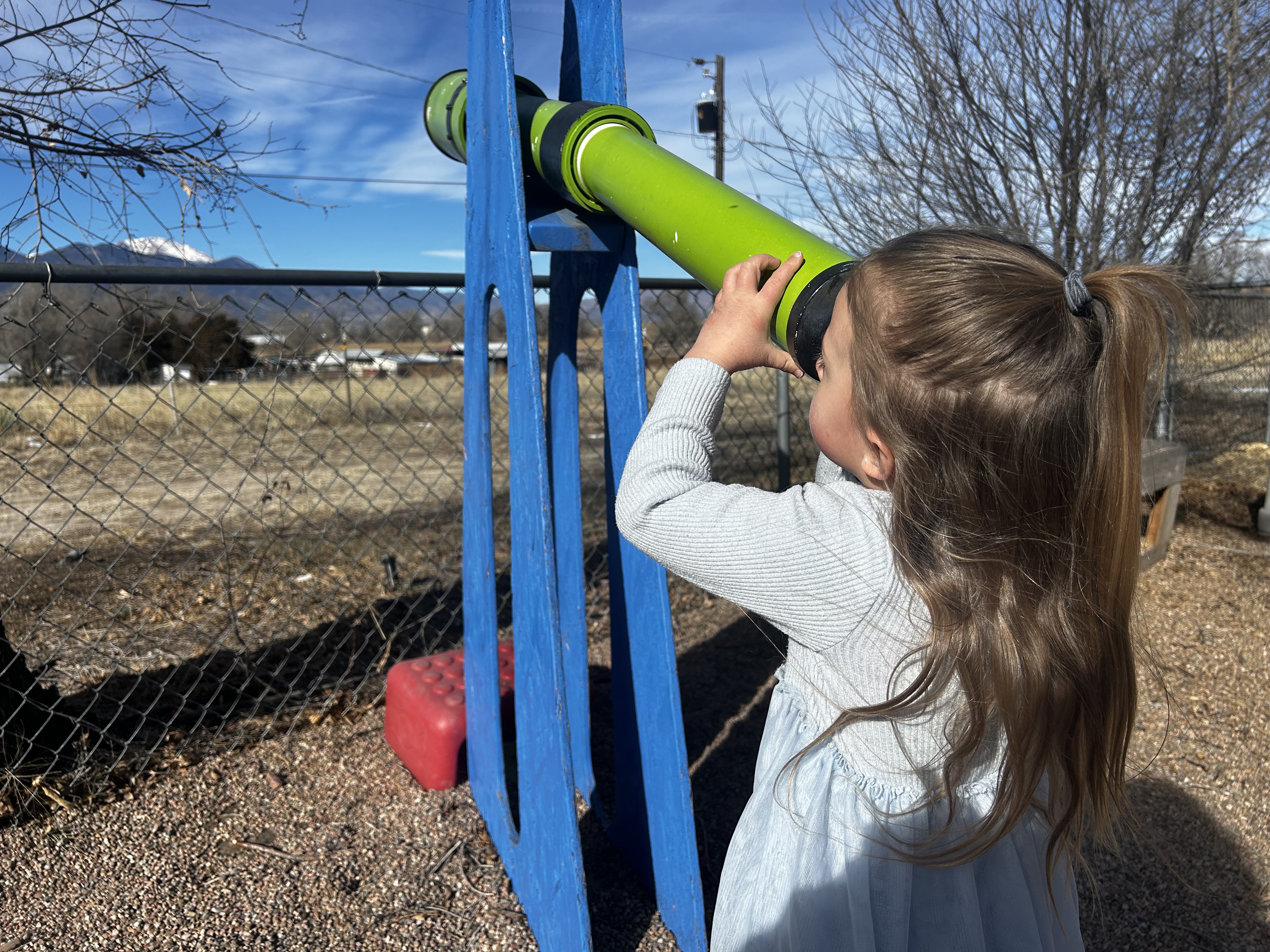Child looking through telescope on playground