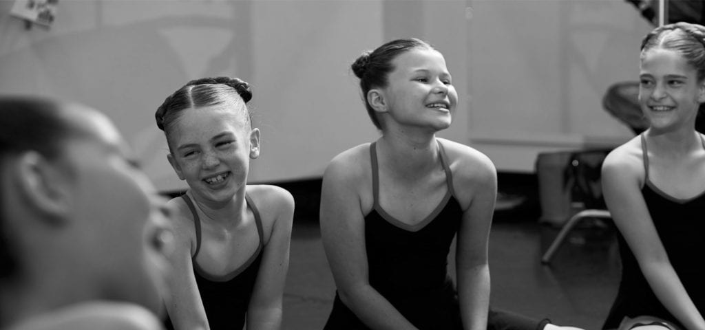 kid dancers sitting around and laughing